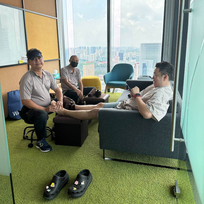 a group of men sitting in a room with a window and a city view