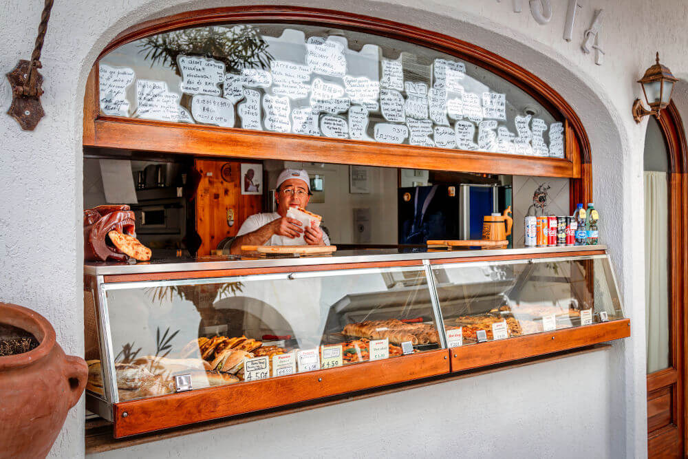 a man behind a counter with food in a window