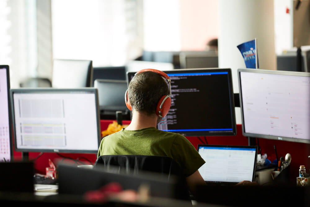a man wearing headphones sitting at a desk with several computers