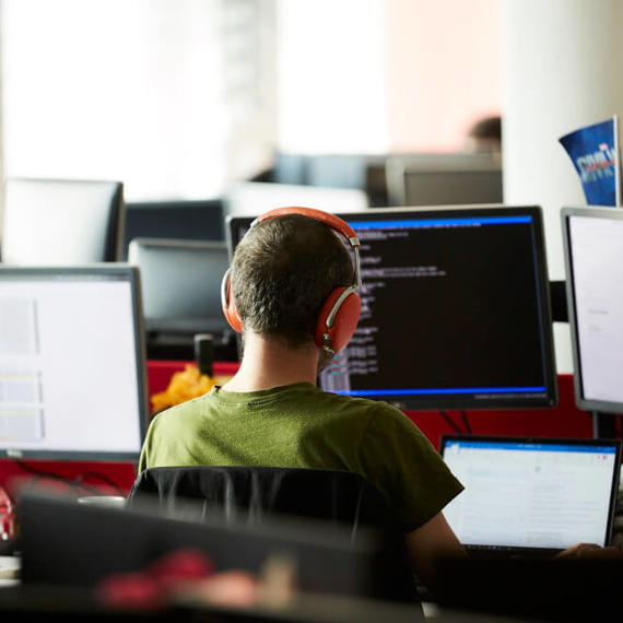 a man wearing headphones sitting at a desk with several computers