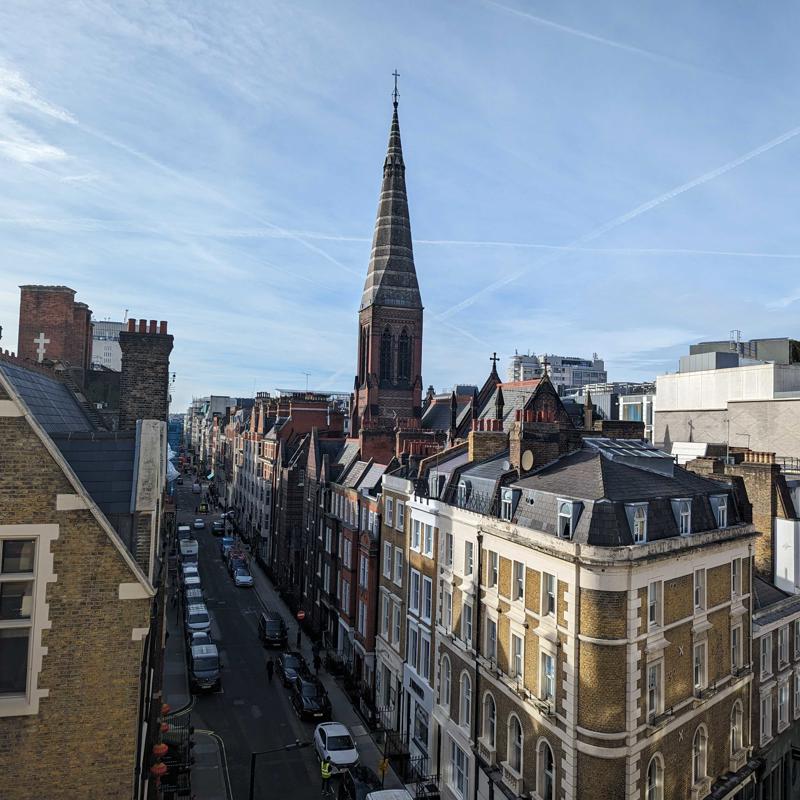 a city street with a tall steeple and cars parked on the side