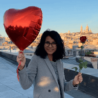 a woman holding a red heart balloon and a rose on a rooftop