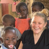 a woman smiling with a group of children
