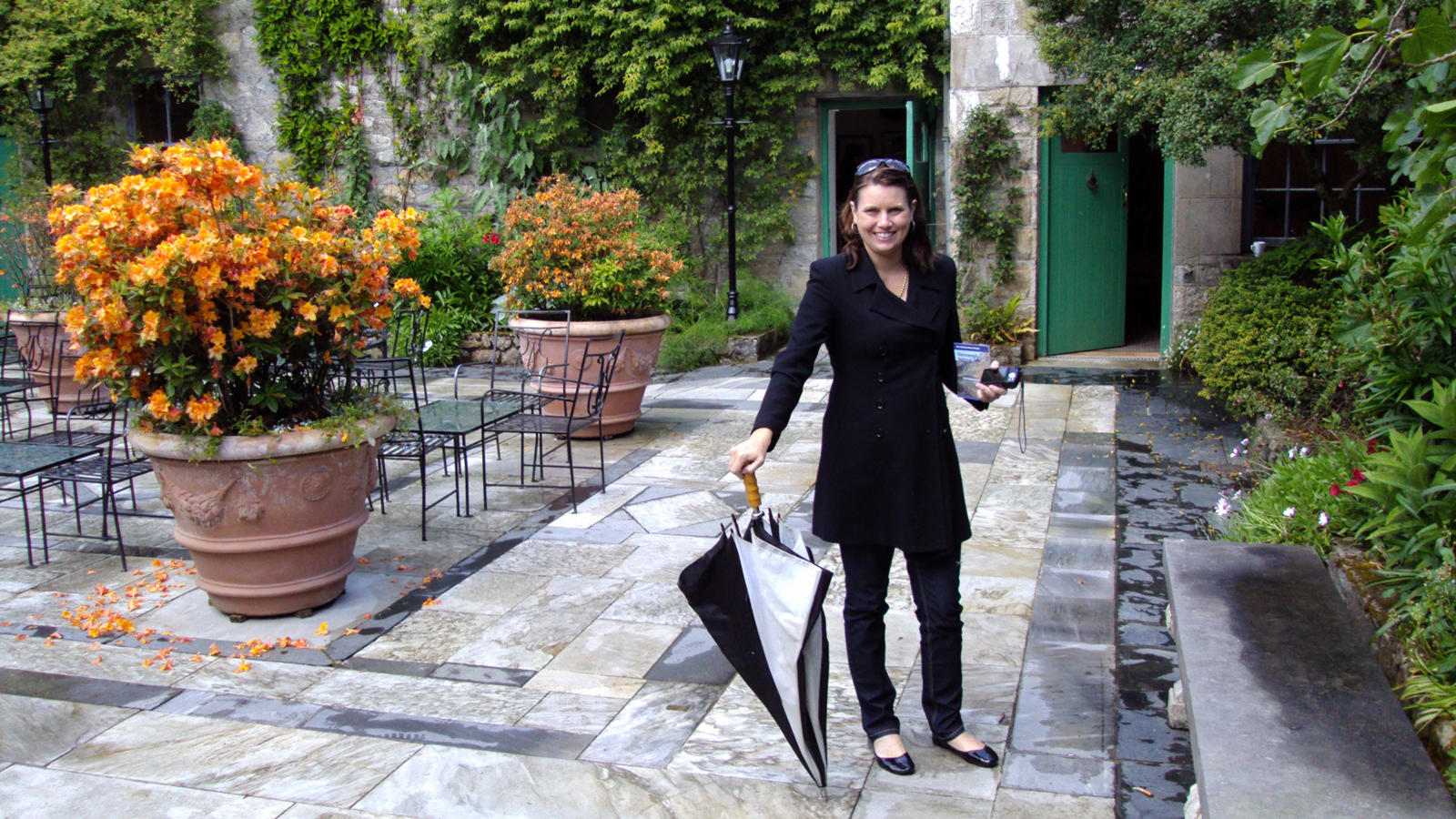 a woman holding an umbrella and standing on a patio
