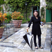 a woman holding an umbrella and standing on a patio