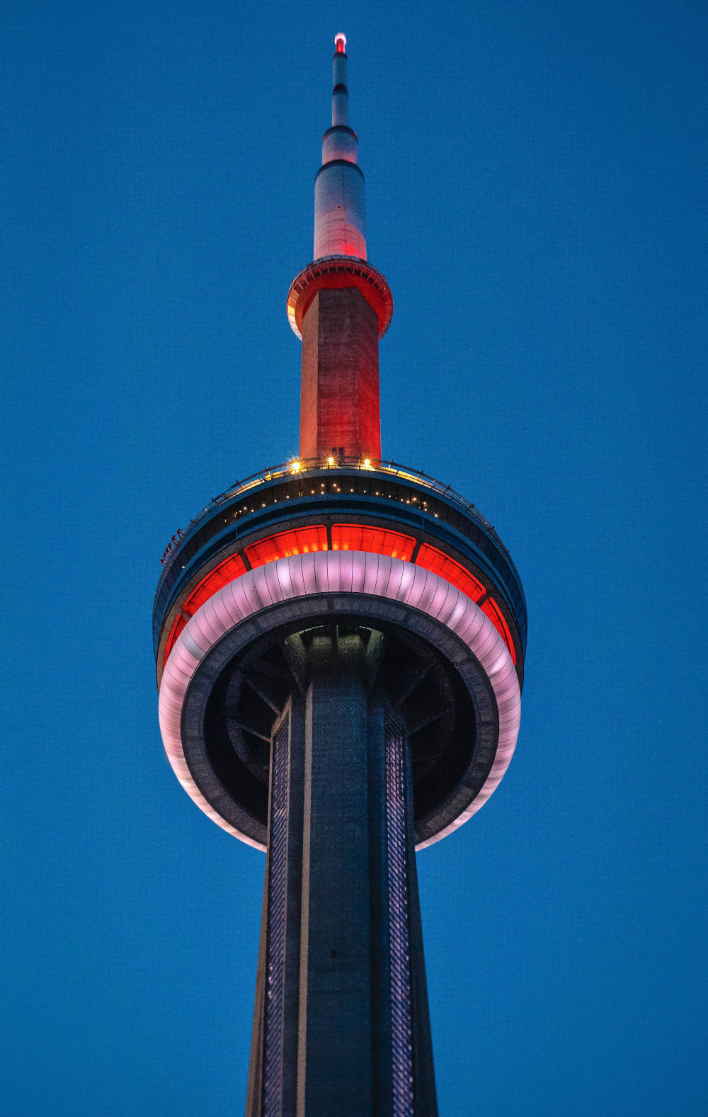 a tall tower with a white and red light with CN Tower in the background
