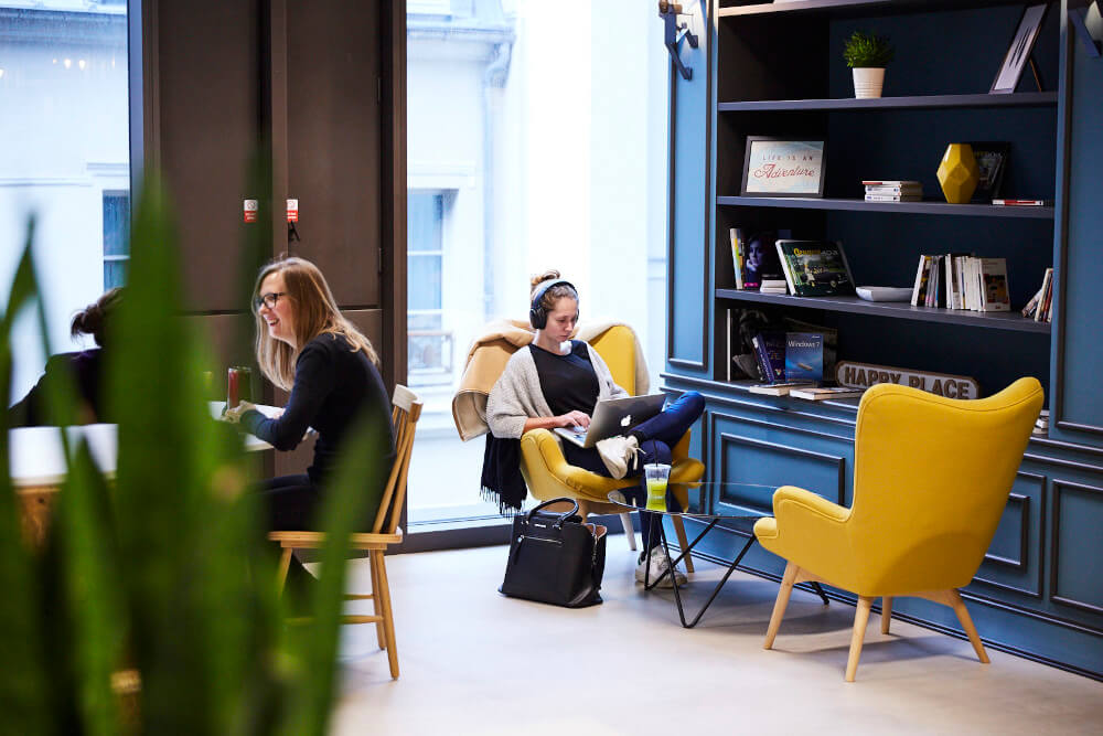 a group of women sitting in chairs and using a laptop