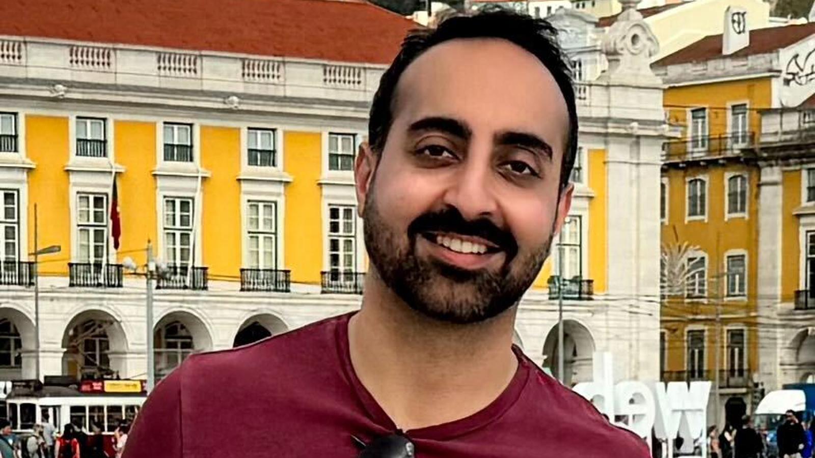 a man smiling in front of a building