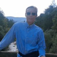 a man wearing sunglasses and standing on a bridge