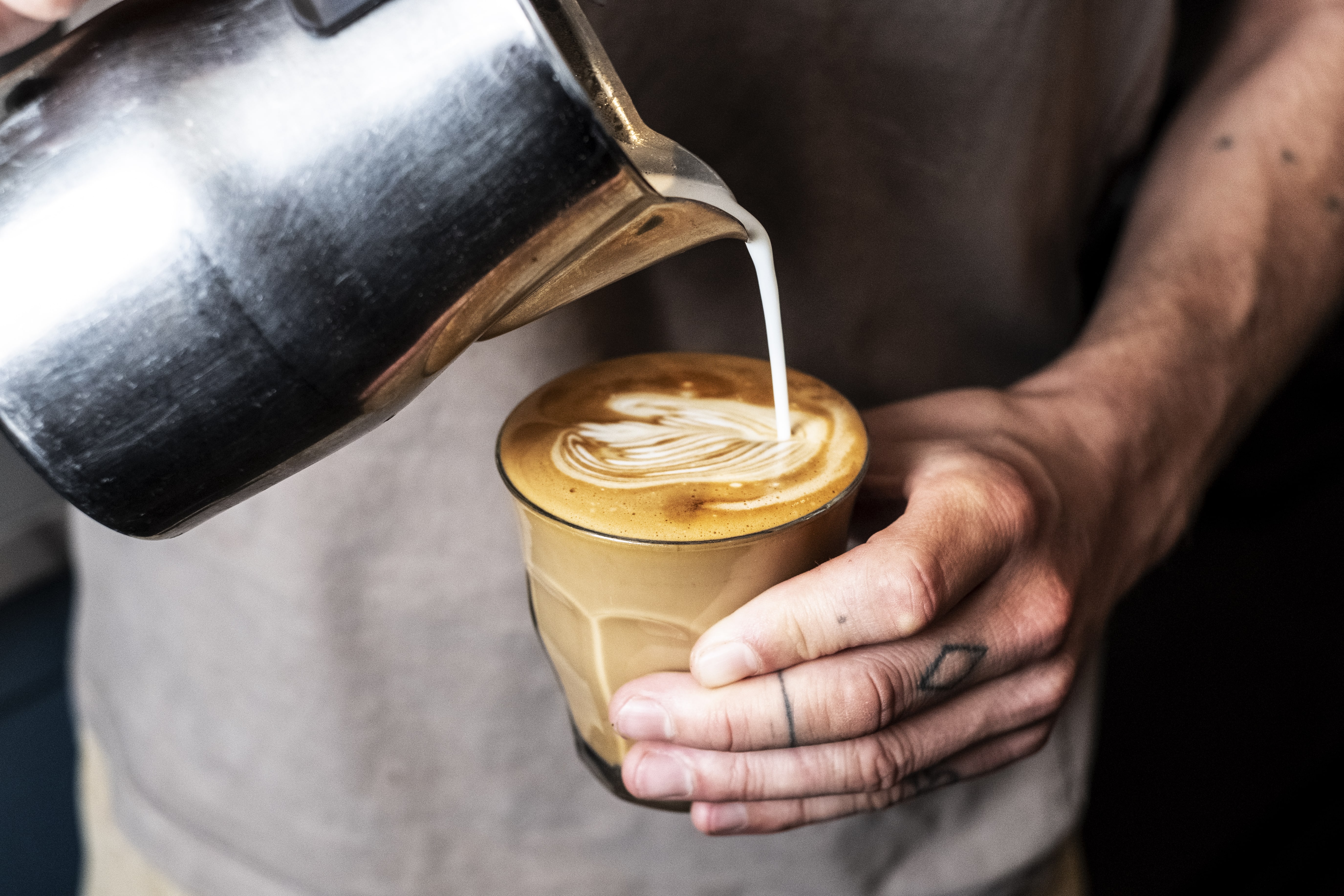 a person pouring milk into a cup of coffee