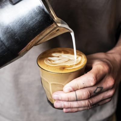 a person pouring milk into a cup of coffee