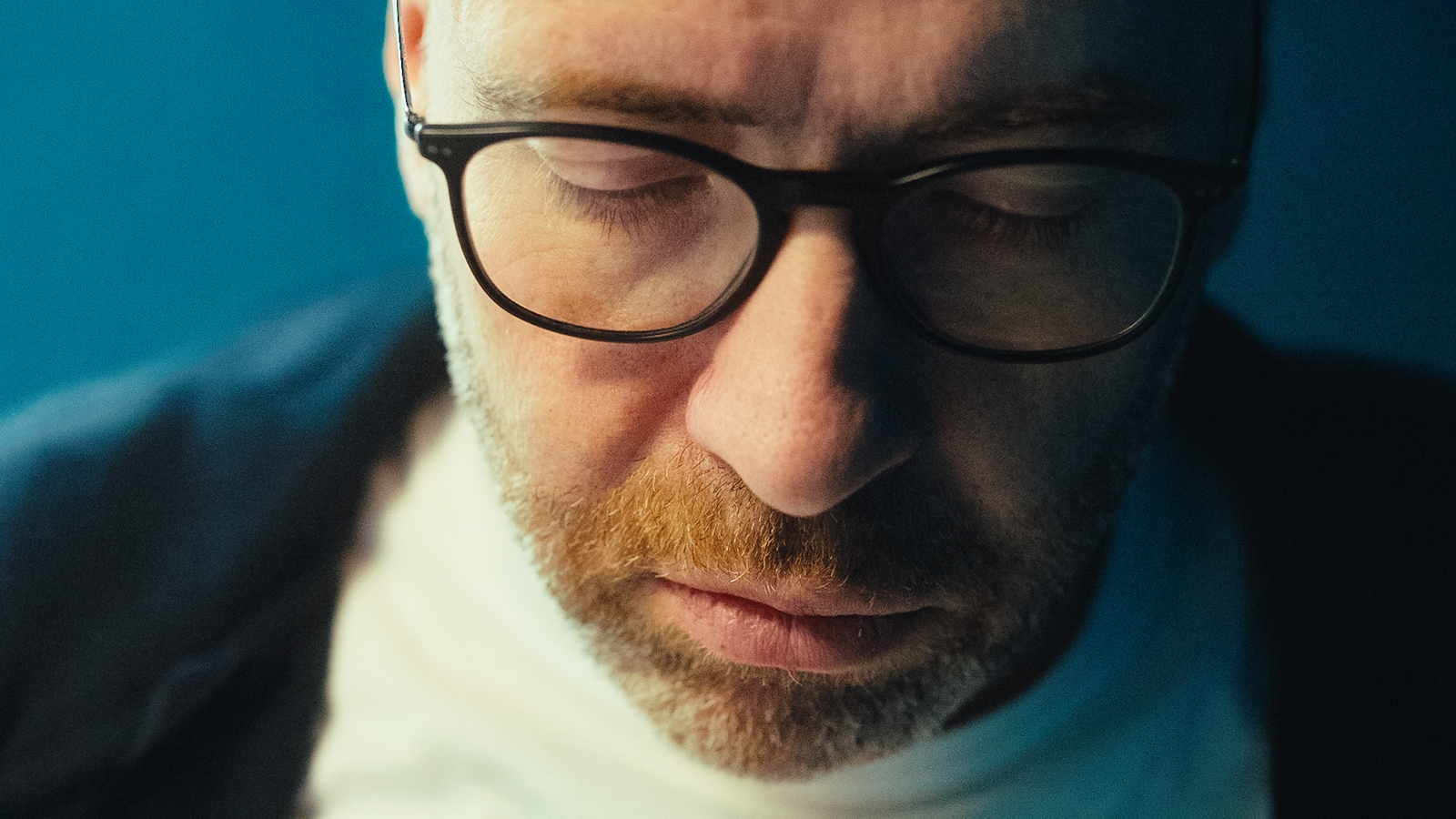 a man with glasses and beard with eyes closed