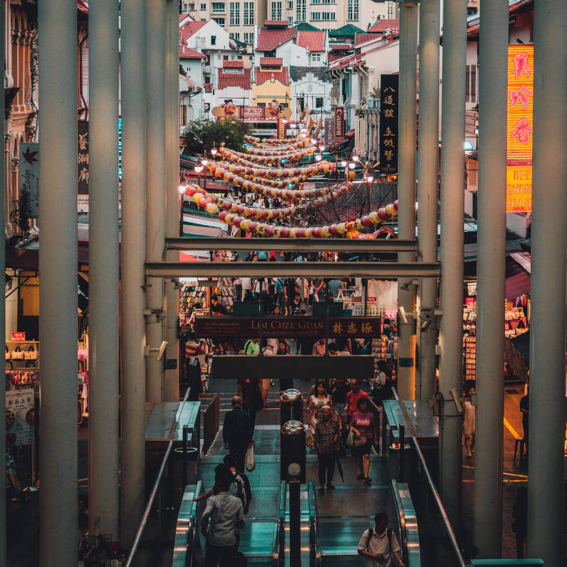 a group of people walking down a walkway in a city