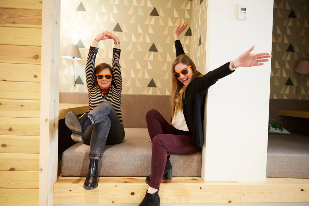 two women sitting on a couch with their arms up