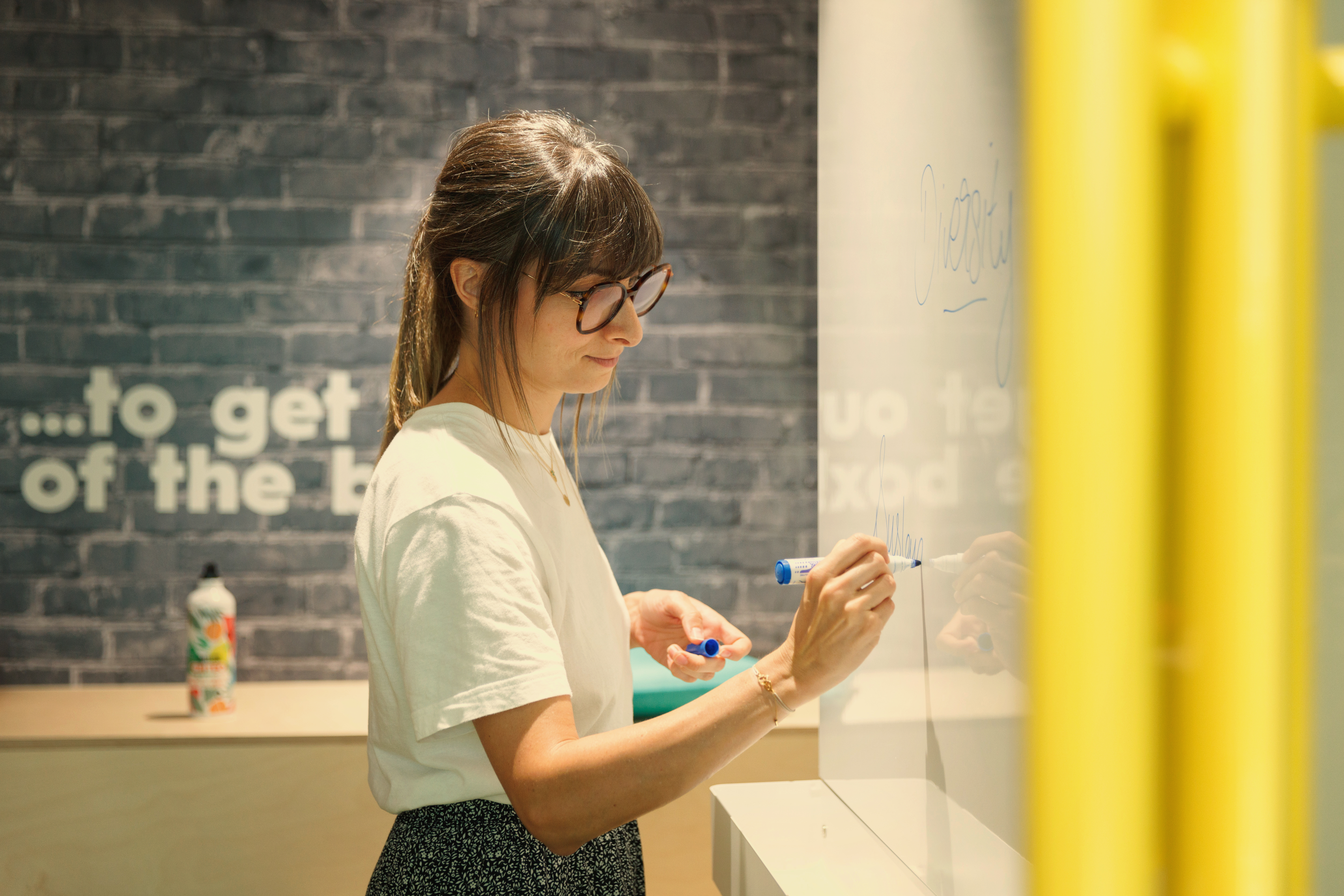 a woman writing on a white board