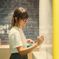 a woman writing on a white board