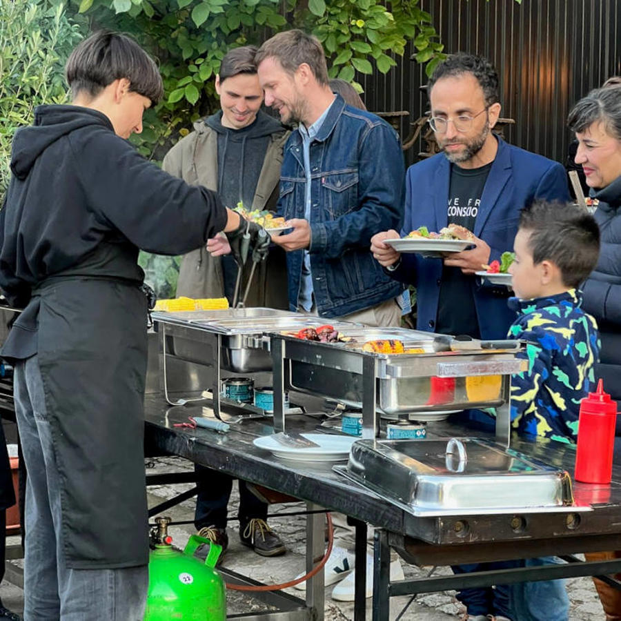 a group of people standing around a table with food