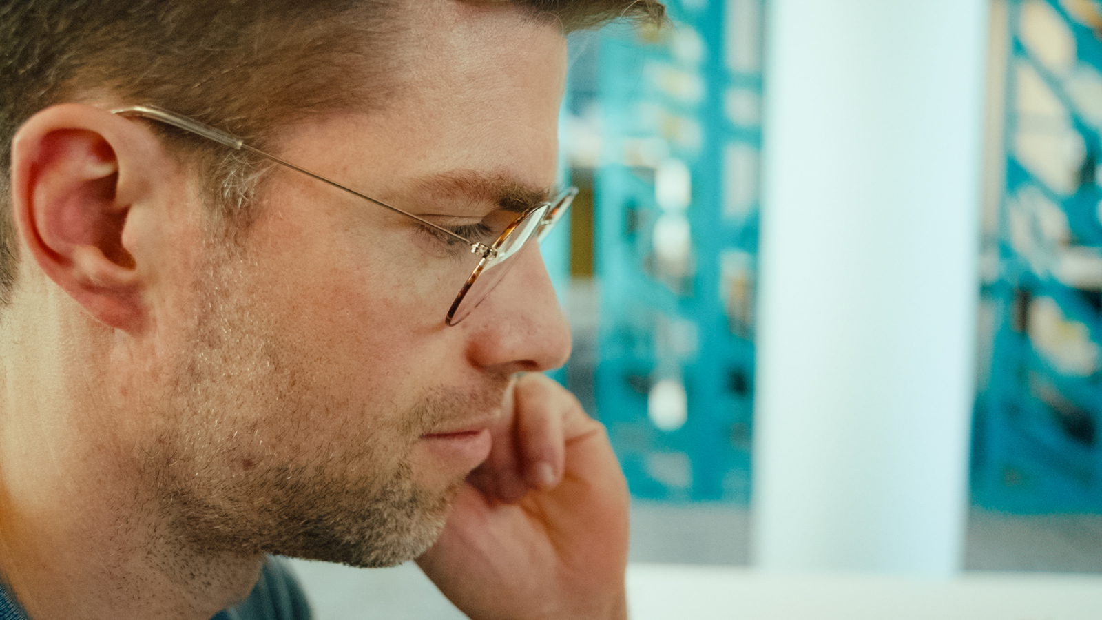 a man wearing glasses and holding his hand to his face