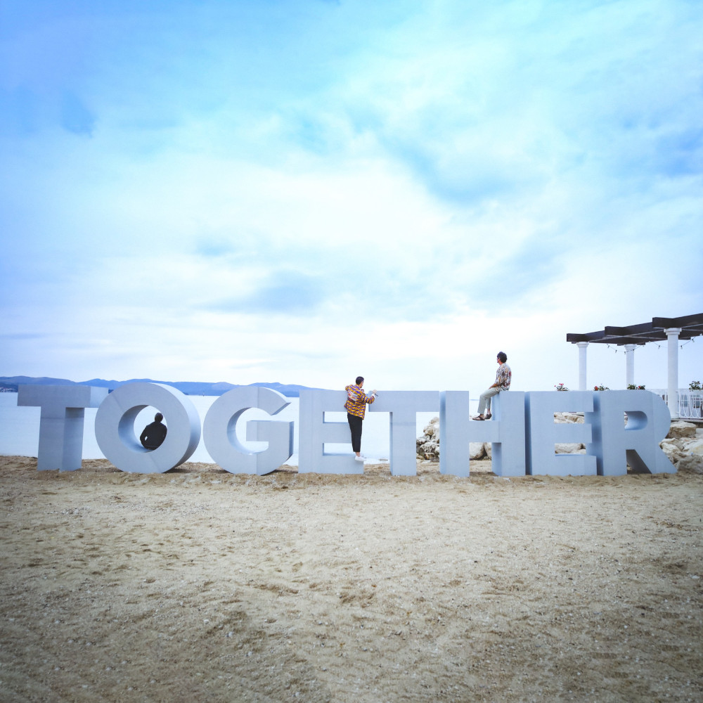 a couple of people standing on a beach with large letters
