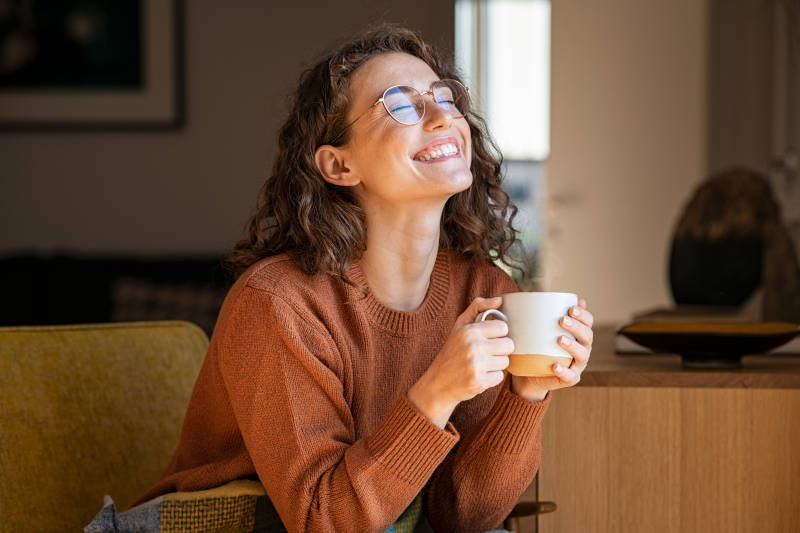 a woman smiling with a cup of coffee