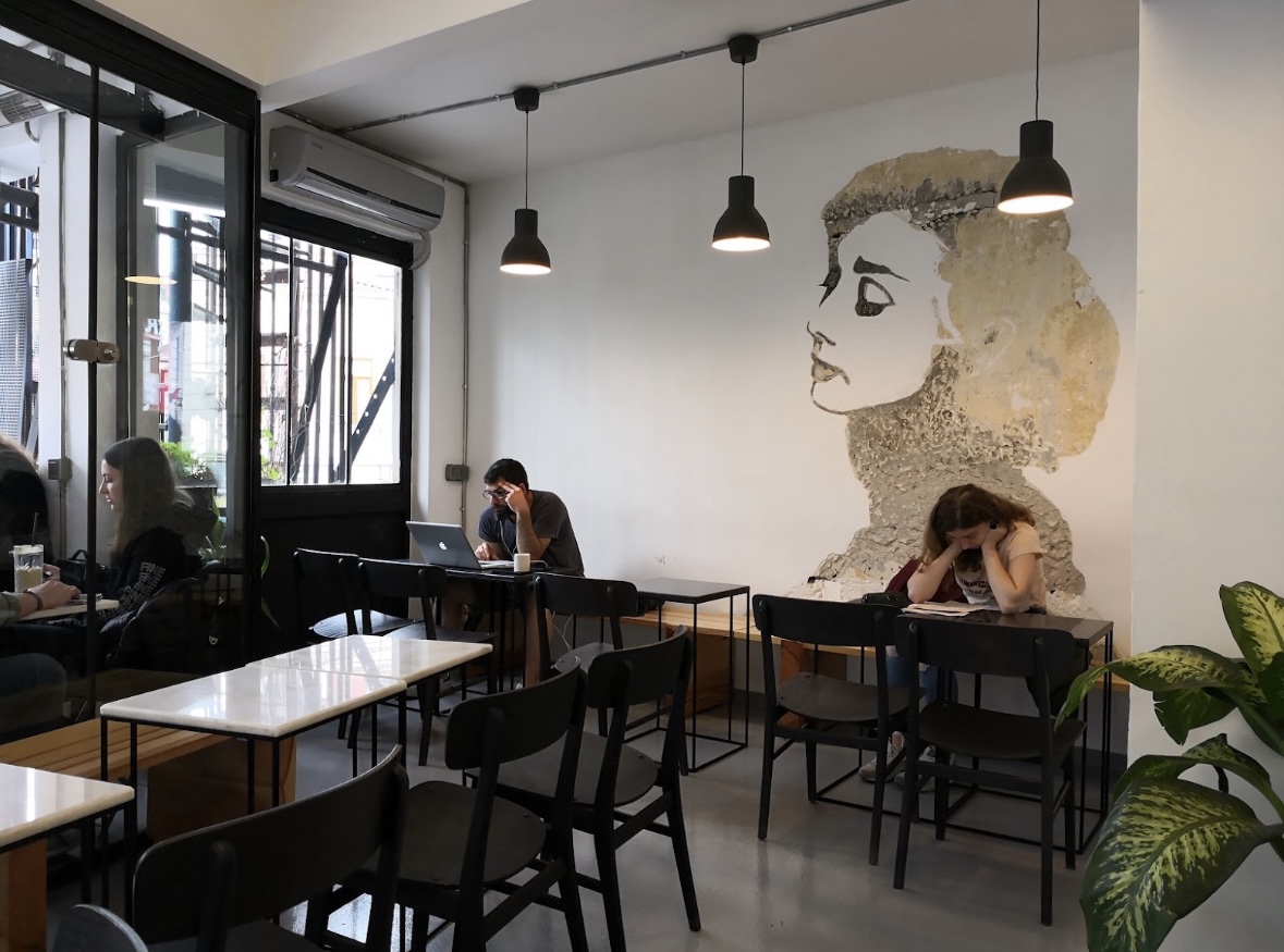 a group of people sitting at tables in a room with a wall art