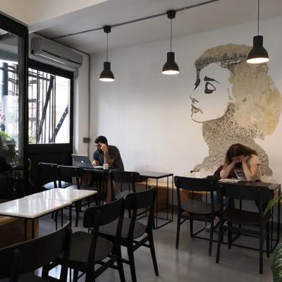 a group of people sitting at tables in a room with a wall art