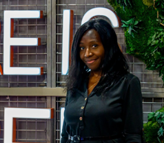 a woman smiling in front of a sign