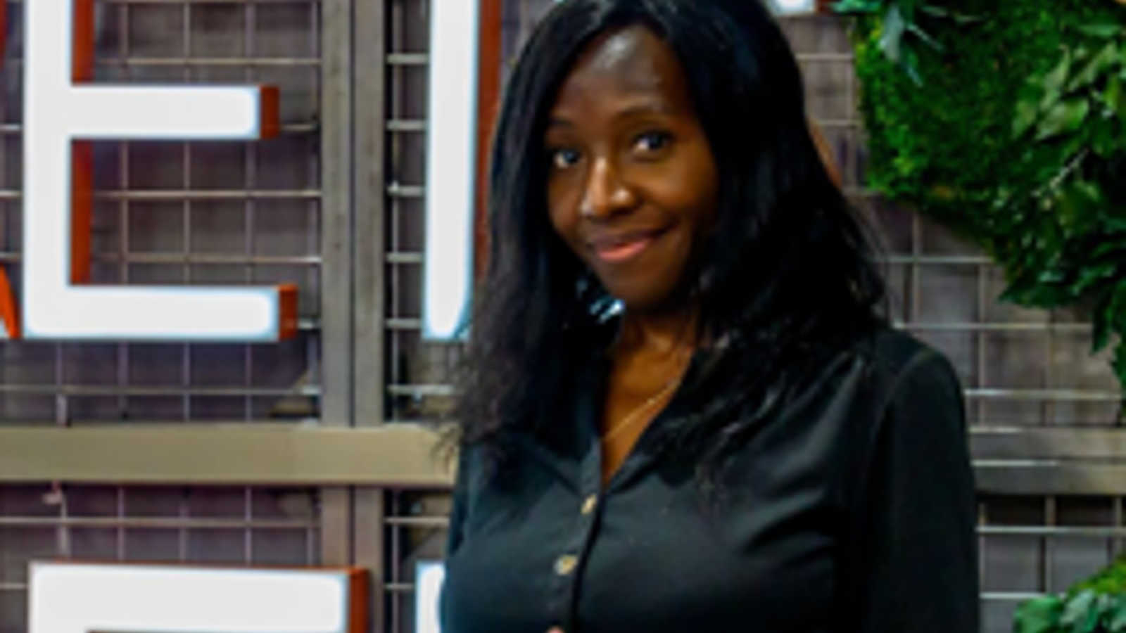 a woman smiling in front of a sign
