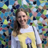 a woman smiling in front of a colorful mosaic wall
