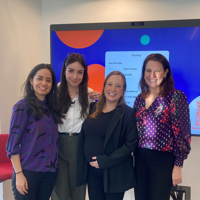 a group of women standing in front of a large screen