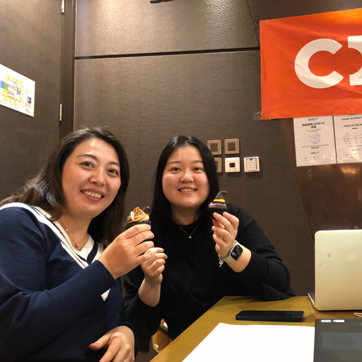 two women sitting at a table holding food