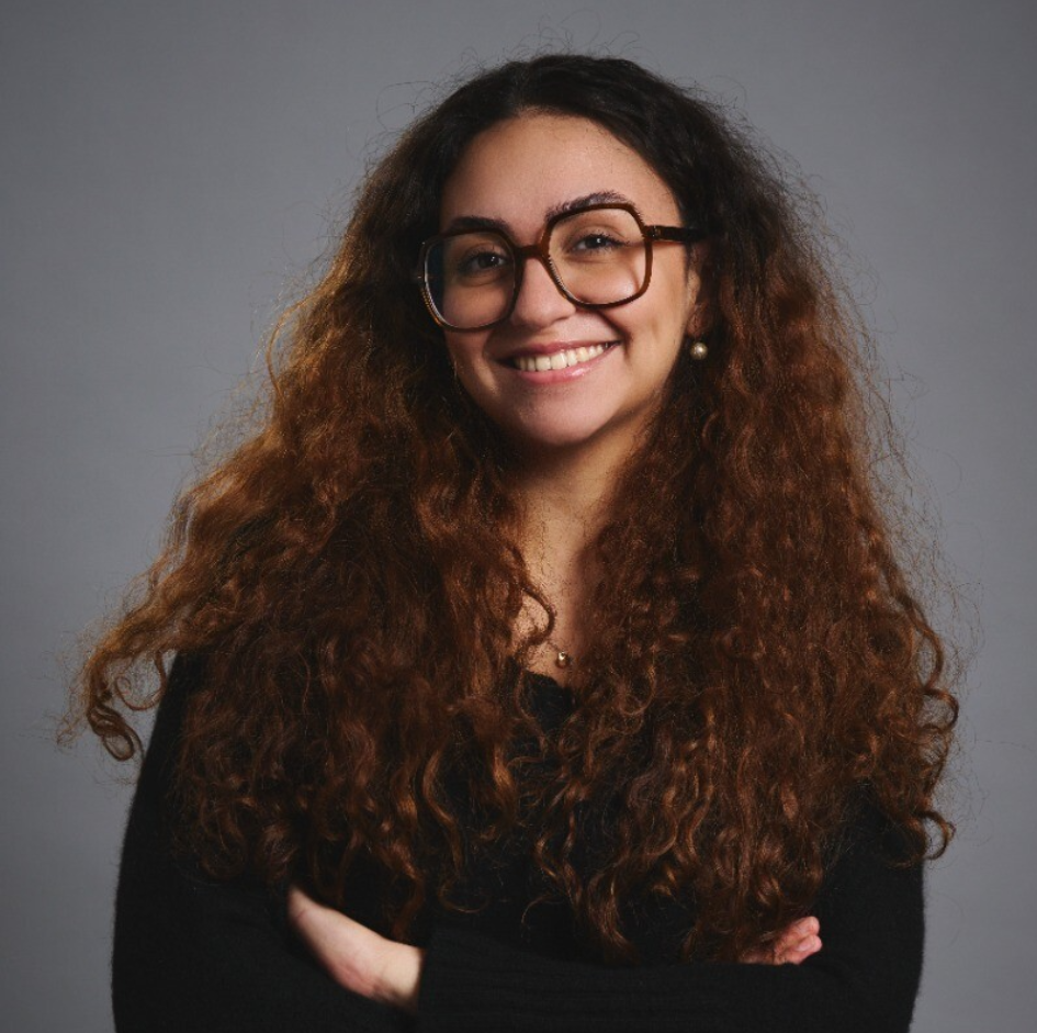 a woman with long curly hair wearing glasses