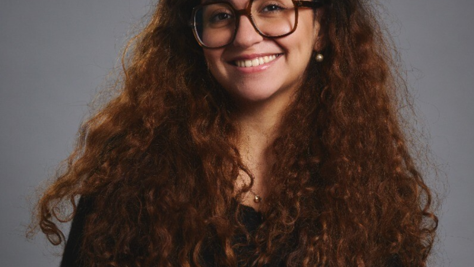 a woman with long curly hair wearing glasses