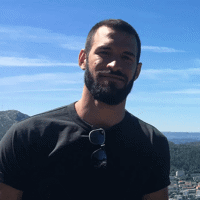 a man standing on a mountain with a city in the background