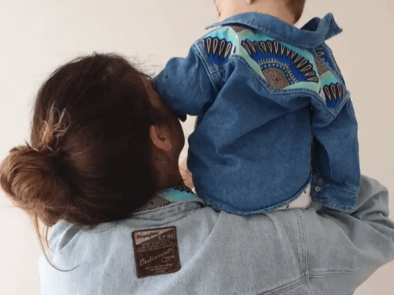 a woman holding a baby on her shoulders