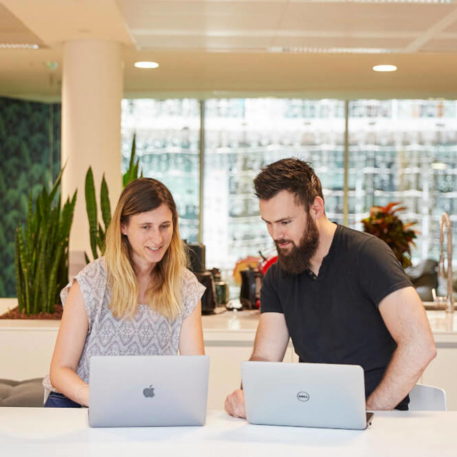 a man and woman looking at laptops