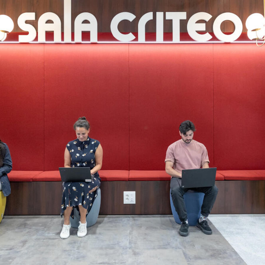 a group of people sitting on benches with laptops