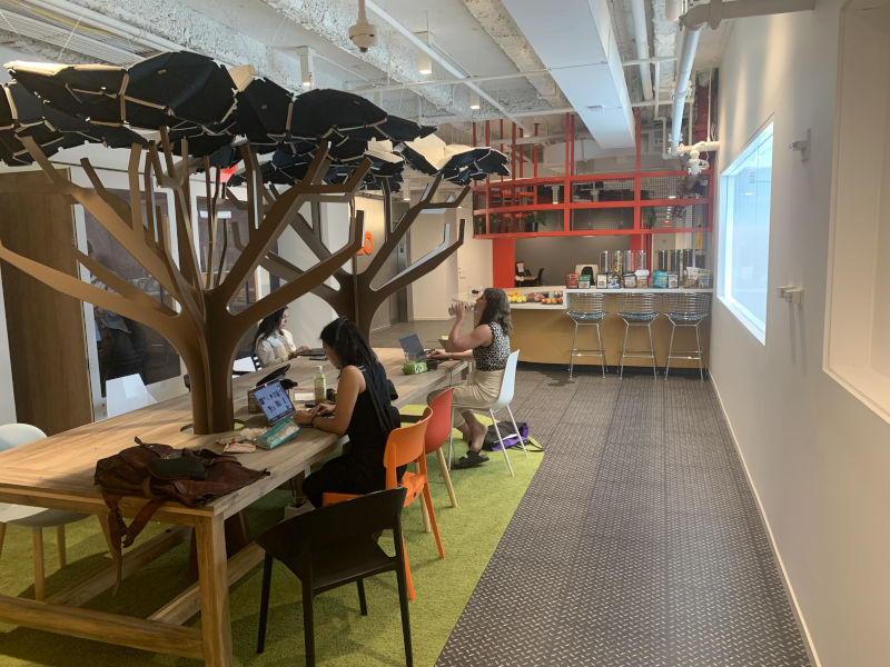 a group of people sitting at a table in a room with a tree shaped object