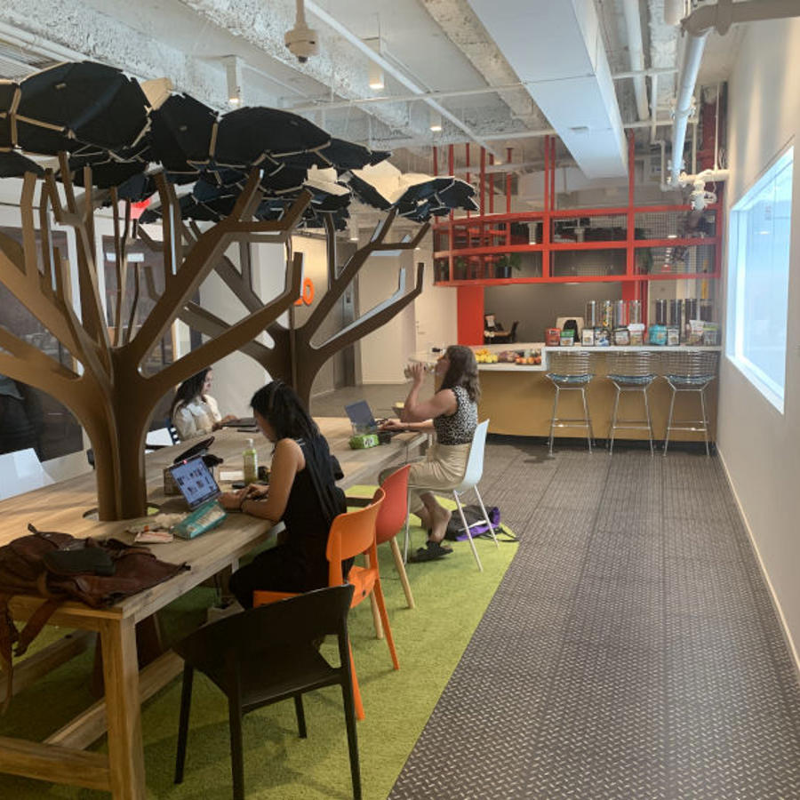a group of people sitting at a table in a room with a tree shaped object