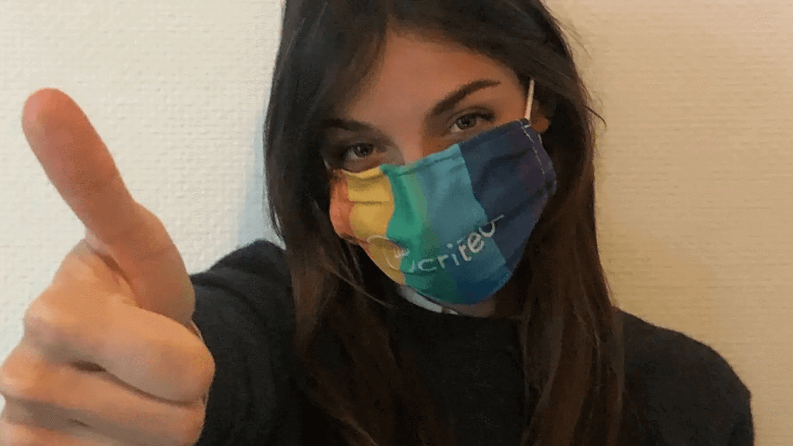 a woman wearing a rainbow colored face mask