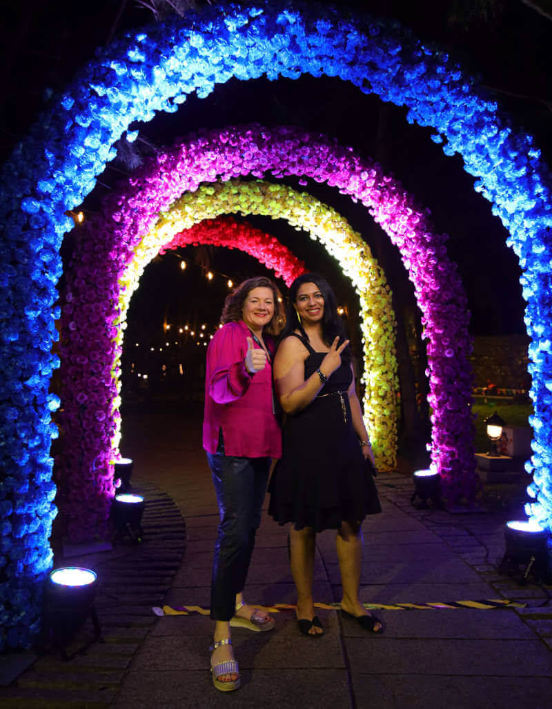 two women standing in front of a colorful arch