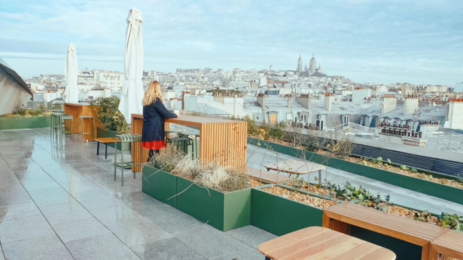 a woman standing on a rooftop terrace overlooking a city