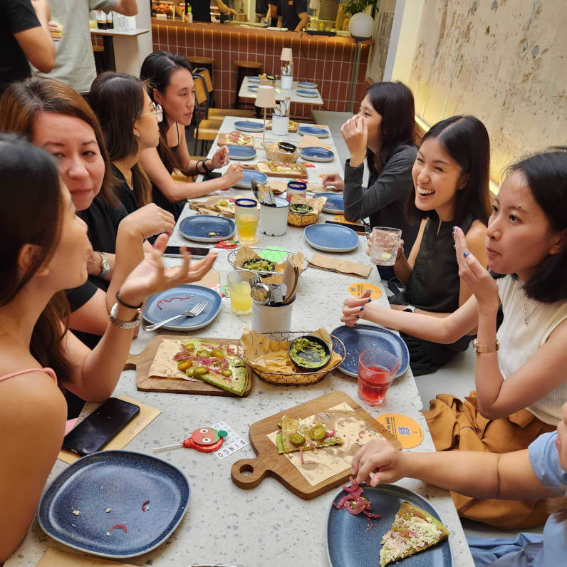 a group of women sitting around a table eating food