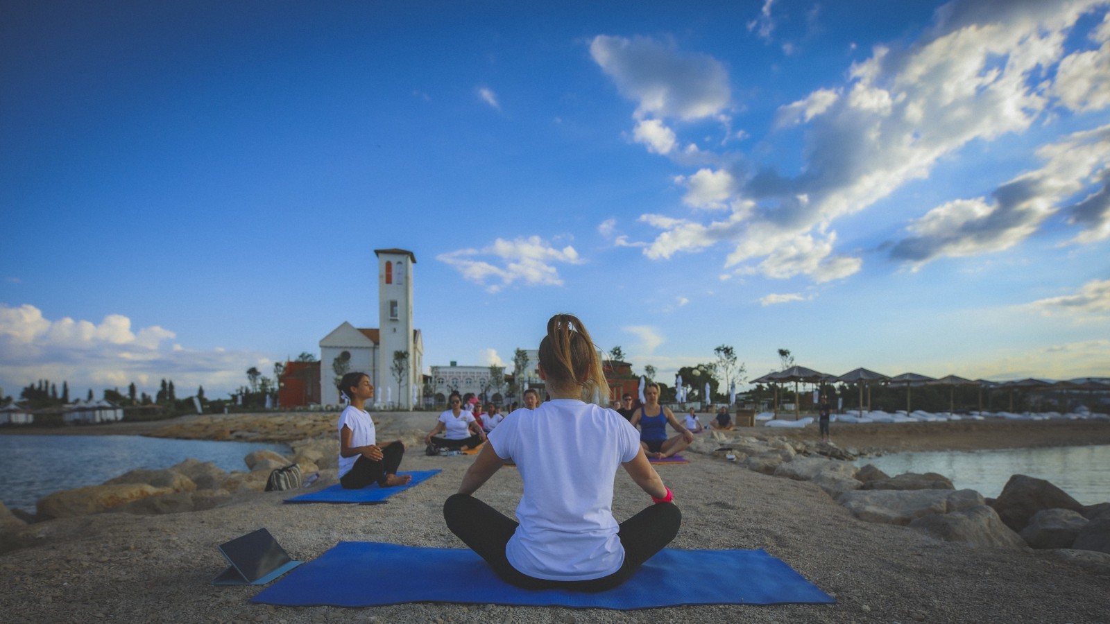 A group of people sitting on yoga mats on the beach.