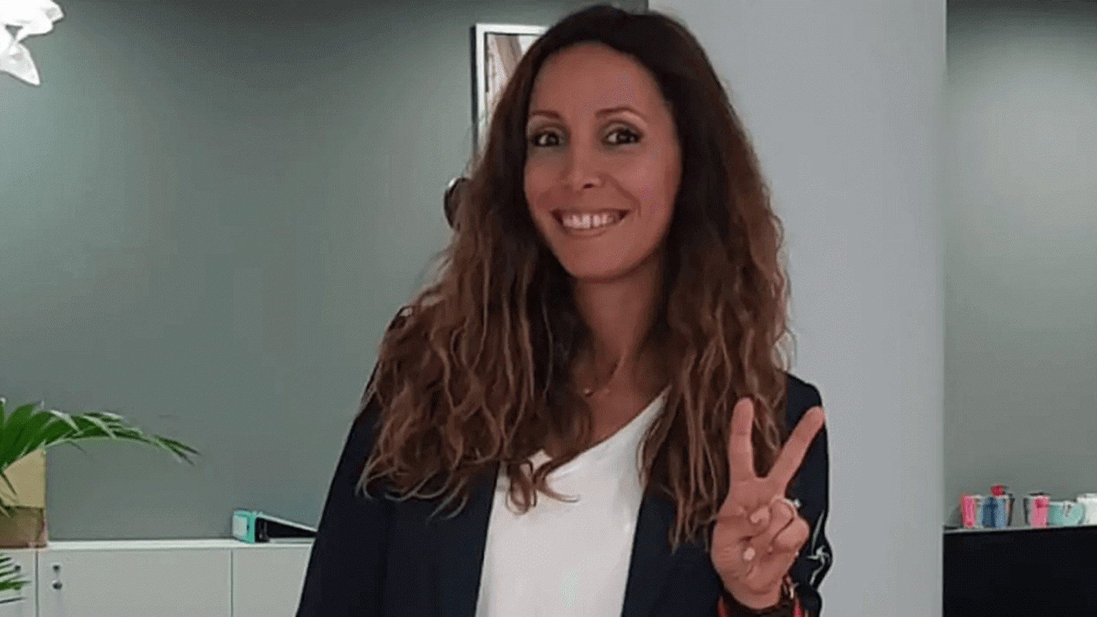 a woman smiling and holding up a peace sign