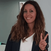 a woman smiling and holding up a peace sign