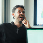 a man laughing with his hand on his face